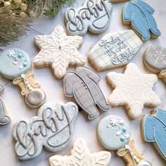 some decorated cookies sitting on top of a white table next to a christmas tree and snowflake