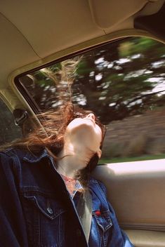 a woman is sitting in the back seat of a car with her head out the window