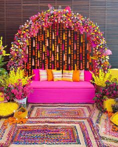 a pink couch sitting in front of a flower covered wall with lots of flowers on it