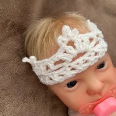 a baby wearing a crochet headband with a pacifier in it's mouth