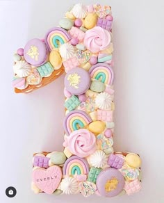 the number one is made up of cookies and candies in pastel pink, yellow, green, blue, purple, and white