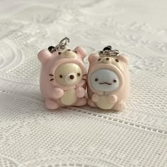 two little pig key chains sitting on top of a bed