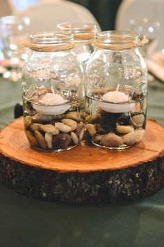 two glass jars filled with rocks on top of a wooden slice