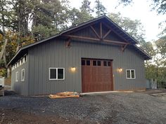 a large garage with two doors on the front and side of it, surrounded by trees