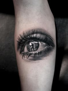 an eye tattoo on the arm with long lashes and a cross in the center is shown