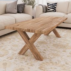 a wooden table sitting on top of a living room floor next to a white couch