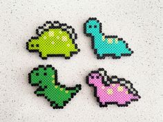 four pixelated dinosaurs sitting on top of a white table next to each other with different colors