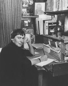 a woman sitting at a desk with books and papers