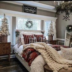 a bedroom decorated for christmas with white and red decorations on the windowsill, plaid bedding, and throw pillows