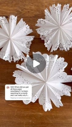 three paper snowflakes sitting on top of a wooden table