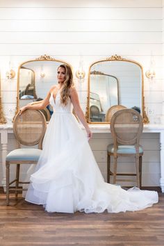 a woman standing in front of a mirror wearing a wedding dress