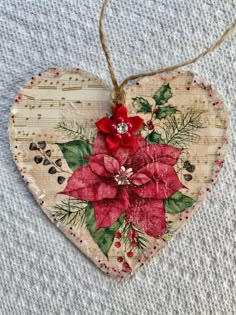 a heart shaped ornament decorated with holly and poinsettis