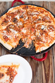 a pizza sitting on top of a pan next to a slice of pizza in a paper plate