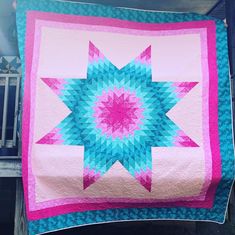 a pink and blue quilt on a bench