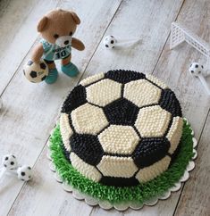 a cake with a soccer ball on it next to a teddy bear and other decorations