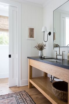 a bathroom with a sink, mirror and rug on the floor in front of it