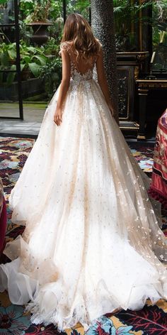 a woman in a wedding dress looking down at the ground with her back to the camera