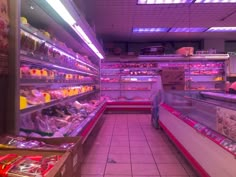 an empty grocery store filled with lots of food and snacks on display in purple lights