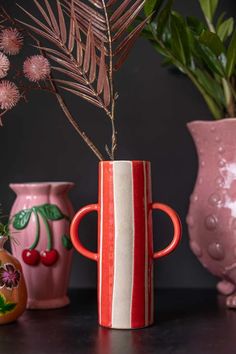 three vases with flowers in them on a table next to plants and other decorative objects