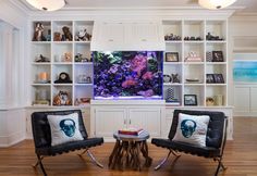 two chairs are in front of a fish tank and bookshelves on the wall