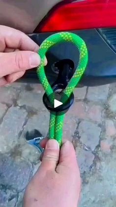 someone is holding a green rope in front of a car with the door handle open