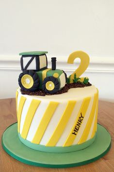 a birthday cake decorated with a tractor and number two on it's side, sitting on top of a wooden table