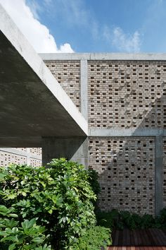 an outdoor area with wooden flooring and brick walls, surrounded by greenery on both sides