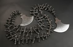 several pieces of metal are arranged together on a black surface, including two large knives and one smaller knife