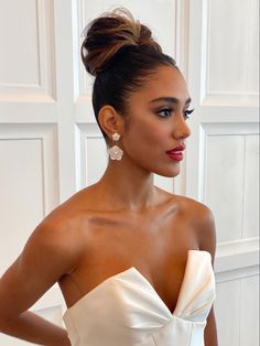 a woman in a strapless white dress with her hands on her hips, looking off to the side