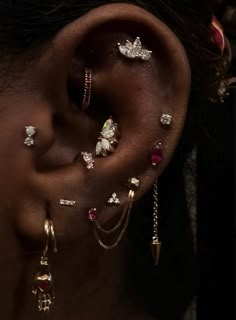 a close up of a person wearing ear piercings and jewelry on their left side