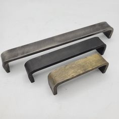 two brass and black drawer pulls on a white surface