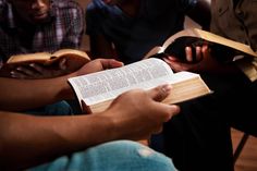 two people holding open books in their hands while one person holds the book with both hands