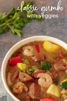 a close up of a bowl of soup with shrimp and veggies on the side