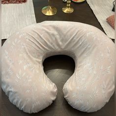 the neck pillow is shaped like an oval cushion with white leaves on it, along with other decorative items