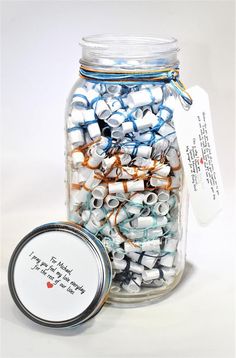 a glass jar filled with lots of small white and blue beads next to a tag