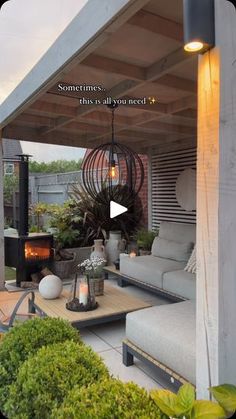 an outdoor living area with couches, table and fire place in the middle of it