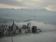 the city is surrounded by fog and low lying clouds