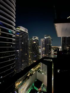 the city skyline is lit up at night with skyscrapers in the foreground and cars on the street below