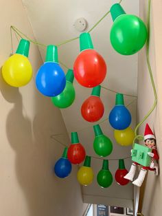 christmas lights hanging from the ceiling with elf on ladder holding an item in front of them