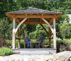 two people sitting at a table under a wooden gazebo