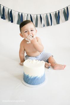 a baby sitting in front of a cake with frosting on it and eating the cake