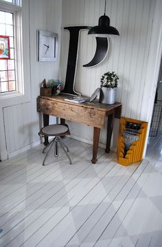 a wooden desk sitting in the middle of a room next to a chair and window