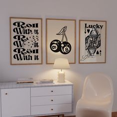 two framed pictures hang on the wall next to a white dresser with a lamp in front of it