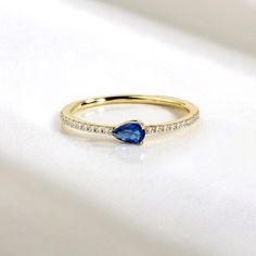 a yellow gold ring with a pear shaped blue sapphire and diamonds