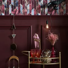 a table with vases, candles and other items on it in front of a red wall