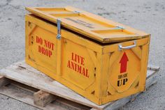 a yellow box sitting on top of a wooden pallet next to a sign that says do not drop