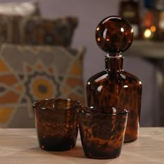 three brown glass vases sitting on top of a wooden table next to a chair