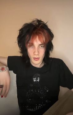 a woman with red hair and piercings on her arm, wearing a black t - shirt