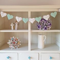 a shelf filled with lots of white shelves covered in paper hearts and decorations on top of it