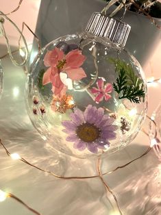 a glass ornament with flowers and lights in the background